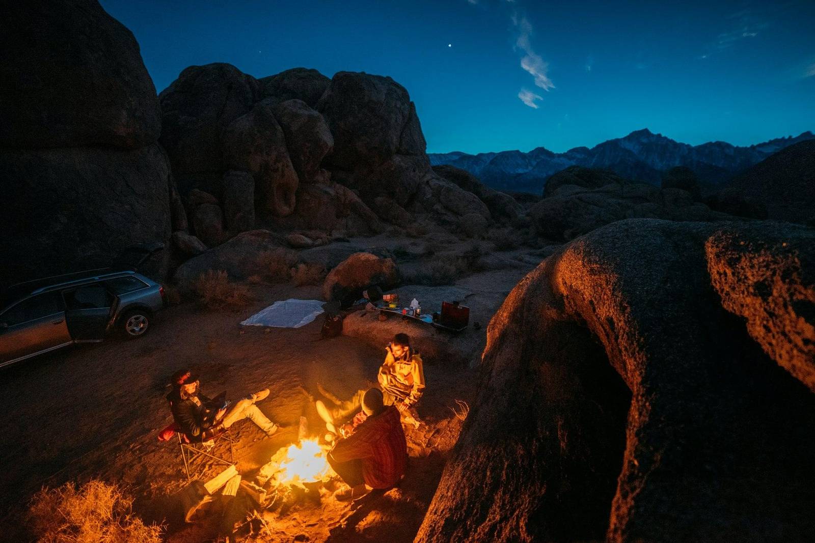 Fogón encendido entre rocas, con cerros al atardecer